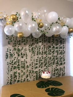 a table topped with a cake and balloons