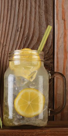 a mason jar filled with lemons and ice sitting on top of a wooden shelf