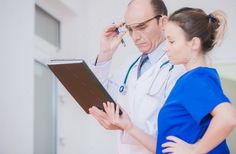 a doctor talking on the phone while holding a clipboard in front of his face