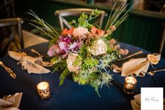 a bouquet of flowers sits on top of a blue table cloth with gold napkins