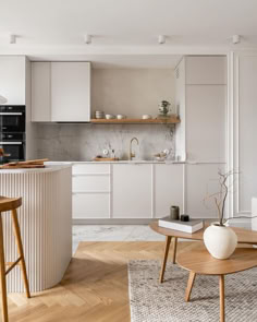 a modern kitchen with white cabinets and wooden stools in the center, along with an island