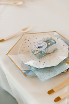 a white table topped with blue and gold paper napkins next to utensils