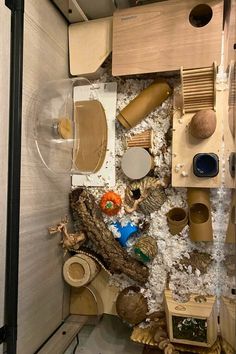 an overhead view of various wooden objects in a room filled with sand and seaweed