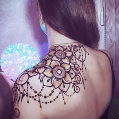 the back of a woman's shoulder with henna tattoos on it