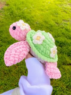 a hand holding a small crocheted turtle on top of it's head