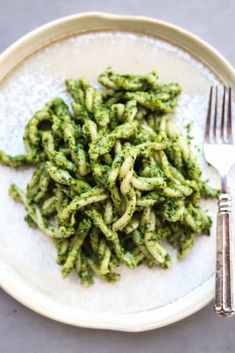 a white plate topped with green pasta covered in pesto