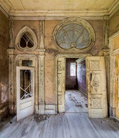 an old run down building with wooden floors and doors that lead to another room in the house