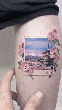 a woman's thigh with flowers and a japanese pagoda tattoo on her left leg