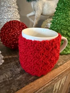 a red and white coffee cup sitting on top of a counter next to christmas decorations