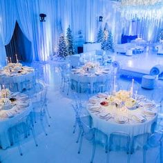 a room filled with tables and chairs covered in white tablecloths next to a christmas tree