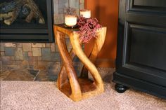 a small wooden table with candles on it next to a fire place in a living room