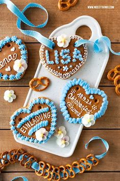 decorated cookies and pretzels on a tray with blue ribbon around the cookie cutters