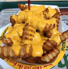 a plate topped with cheesy waffle fries covered in yellow sauce and melted cheese