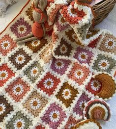 a crocheted blanket and two teddy bears on a table next to a basket