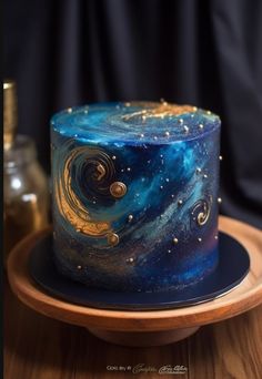 a blue and gold galaxy cake on a wooden plate