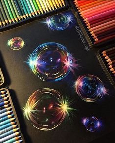 colored pencils are laying next to a drawing book with an image of soap bubbles on it