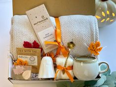 an assortment of items in a box on a table with candles, tea bags and towels