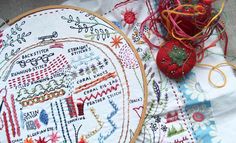 two embroidery hoops are sitting next to each other on a table with some red and yellow thread