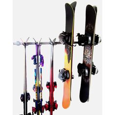 three snowboards and two skis are hanging on a rack with other items attached to it