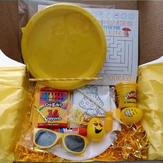 a yellow box with some items in it that include sunglasses, sun glasses and candy