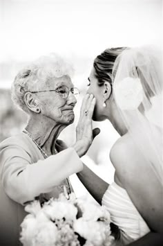 an older woman is touching the bride's face