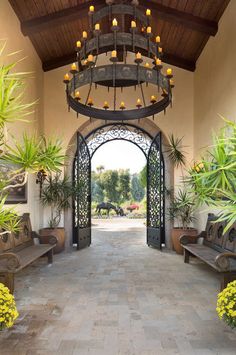 an open entry way with benches and potted plants on either side, surrounded by greenery