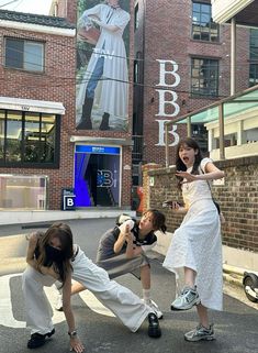 three people taking pictures in front of a building with a giant billboard on it's side