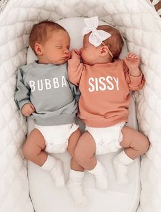 two babies laying next to each other on top of a white blanket in a basket