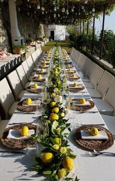 a long table is set with lemons and greenery for an outdoor dinner party