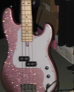 a pink and white bass guitar sitting on top of a table