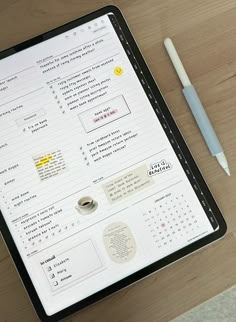 a tablet computer sitting on top of a wooden table next to a pen and paper