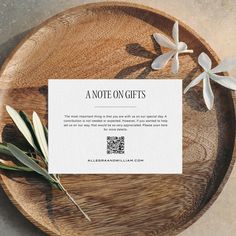 a note sitting on top of a wooden plate next to some white flowers and leaves