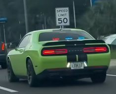 a green car driving down the road with a speed limit sign on it's back