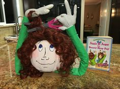 a large stuffed doll sitting on top of a counter next to a children's book