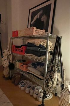 a metal shelf filled with lots of shoes and other items next to a painting on the wall