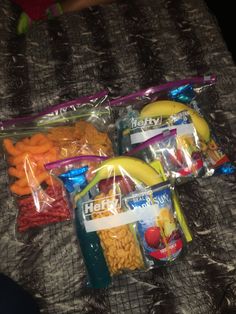 three plastic bags filled with different types of food on top of a bed next to each other