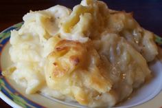 a white plate topped with macaroni and cheese covered in gravy on top of a table