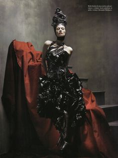 a woman in a black dress sitting on top of a red cloth covered tablecloth