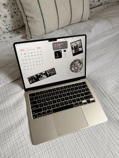 an open laptop computer sitting on top of a white bed covered in pillows and blankets