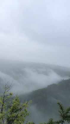 the mountains are covered in thick fog and low lying clouds, as seen from an overlook point