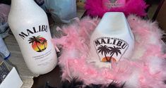 two bottles and some pink feathers on a table