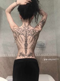 a woman with tattoos on her back standing in front of a toilet