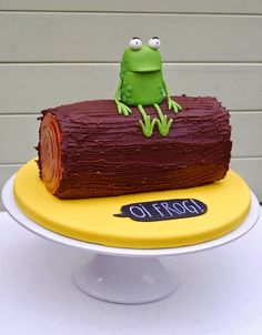 there is a cake that looks like a log with a frog sitting on top of it