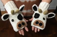 two hands wearing knitted cow mitts on top of a wooden table