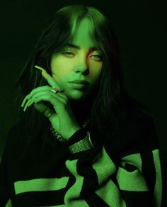 a woman with long black hair and green eyes is posing for a photo in the dark