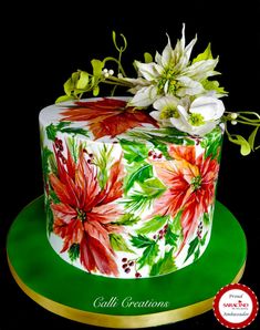 a decorated cake with flowers on it sitting on a green plate next to a red and white ribbon