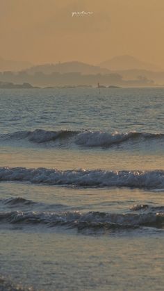 two surfers in the ocean at sunset with mountains in the backgrouund