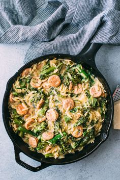 pasta with shrimp and broccoli in a black skillet on a gray surface