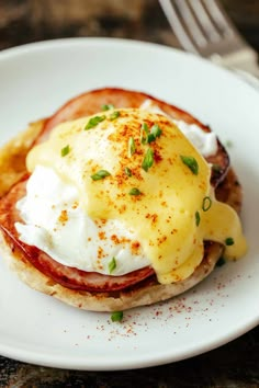 an english muffin with eggs and bacon on it is served on a white plate