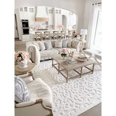 a living room filled with lots of furniture and flowers on top of a white rug